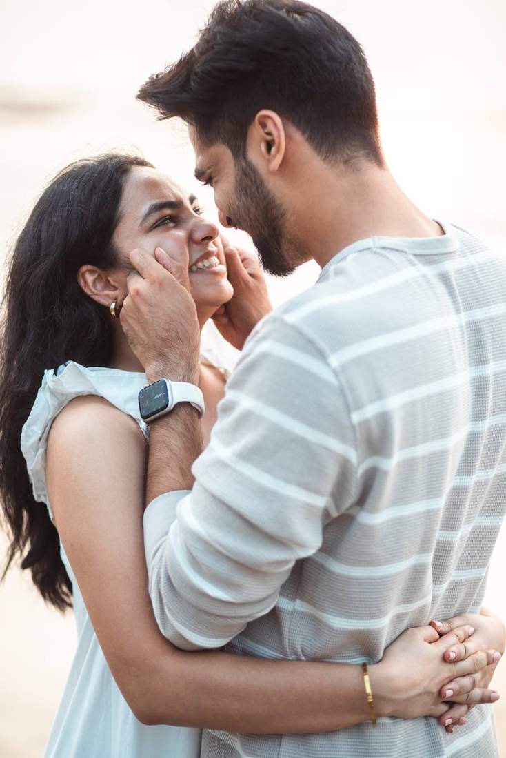 Couple smiling closely, foreheads touching, on the beach