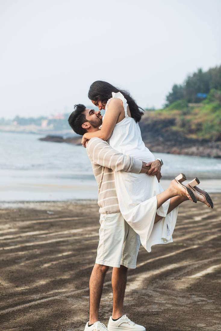 Groom lifting bride off her feet for a kiss on the beach