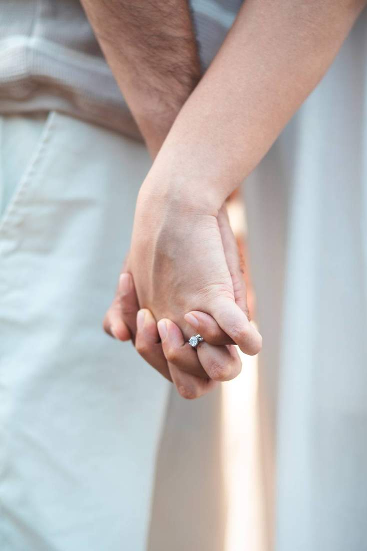 Close-up of the couple holding hands, engagement ring visible