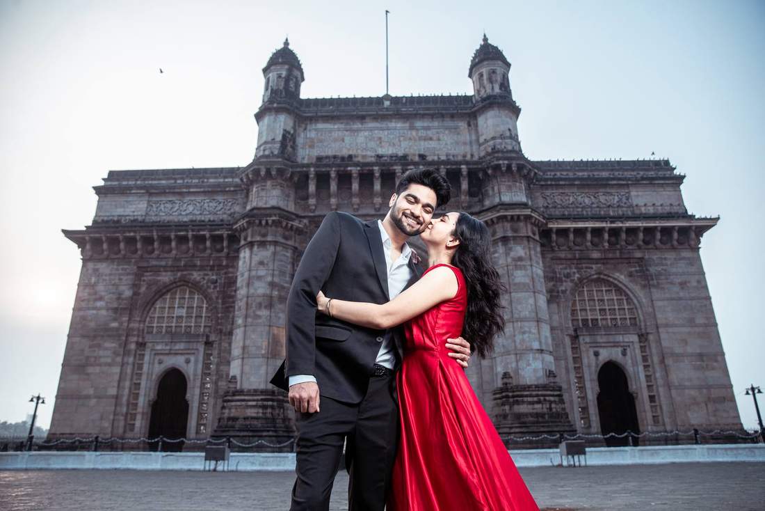 Bride kissing groom's cheek before the Gateway of India