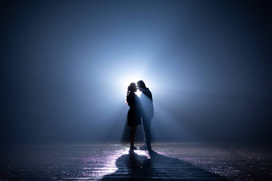 Couple silhouetted and backlit, foreheads together at dusk