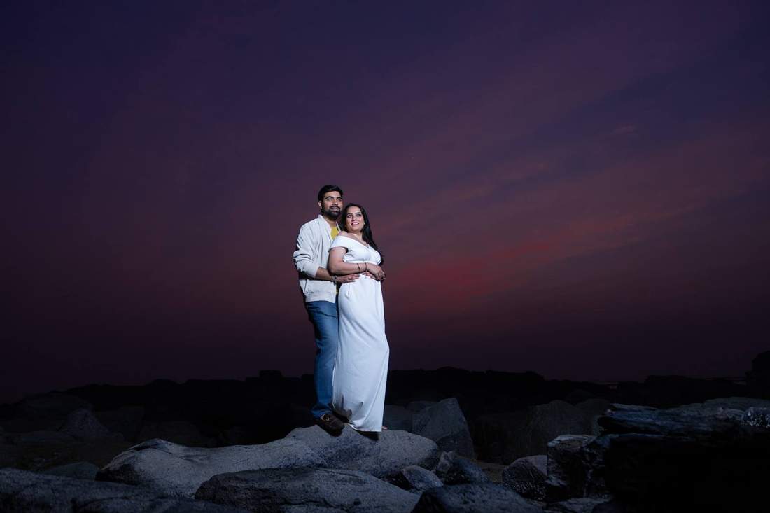 Couple embracing on coastal rocks at dusk