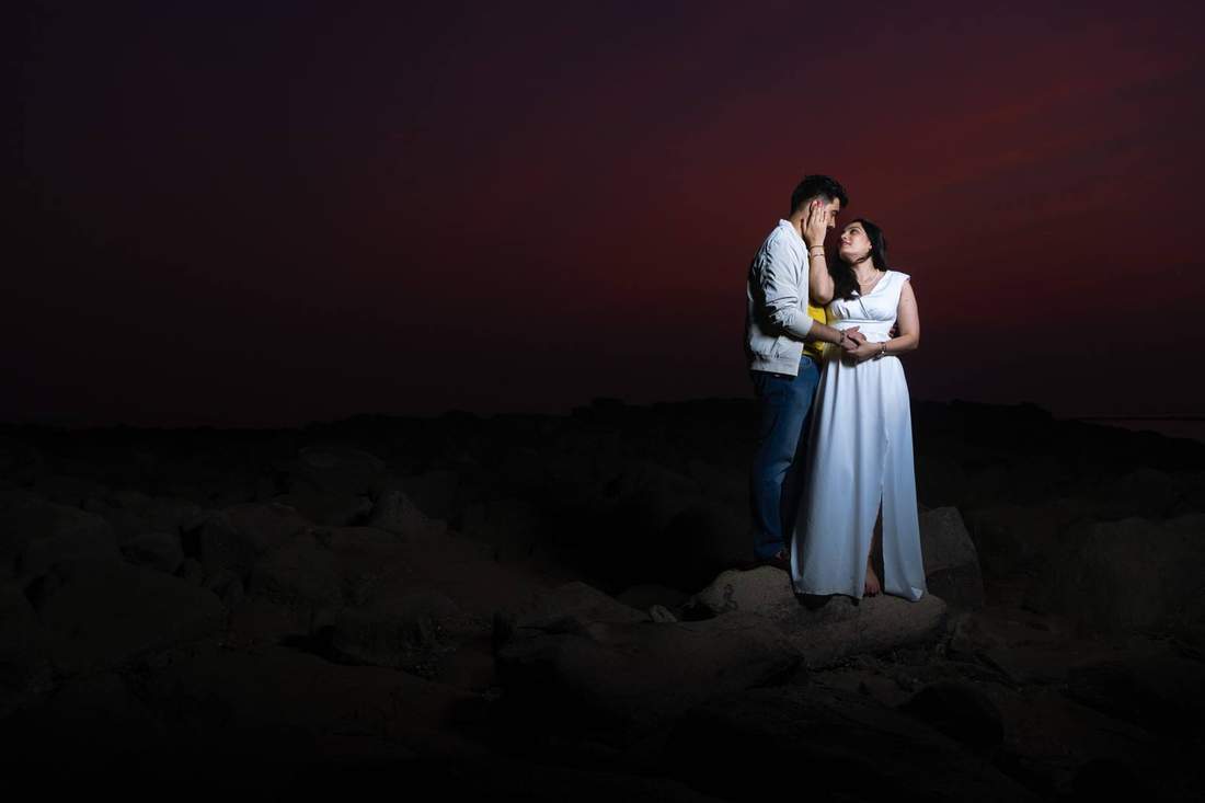 Couple sharing a tender touch on rocks at dusk