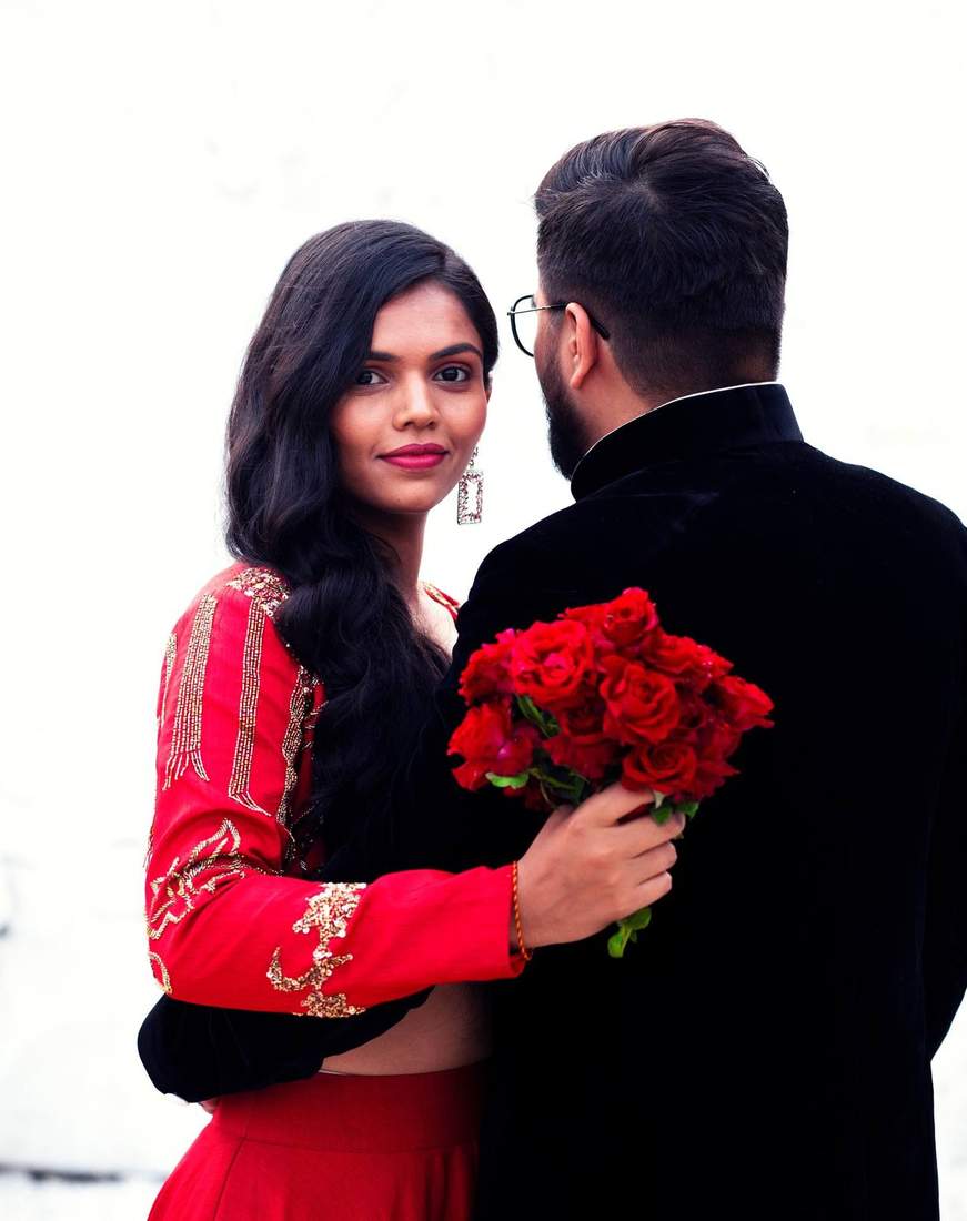 Bride holding a bouquet of red roses, glancing back at the camera