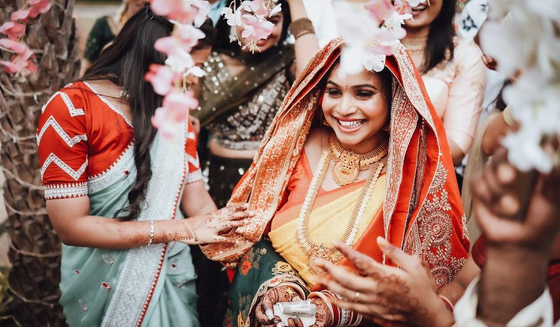 Bride laughing under a floral toran with family