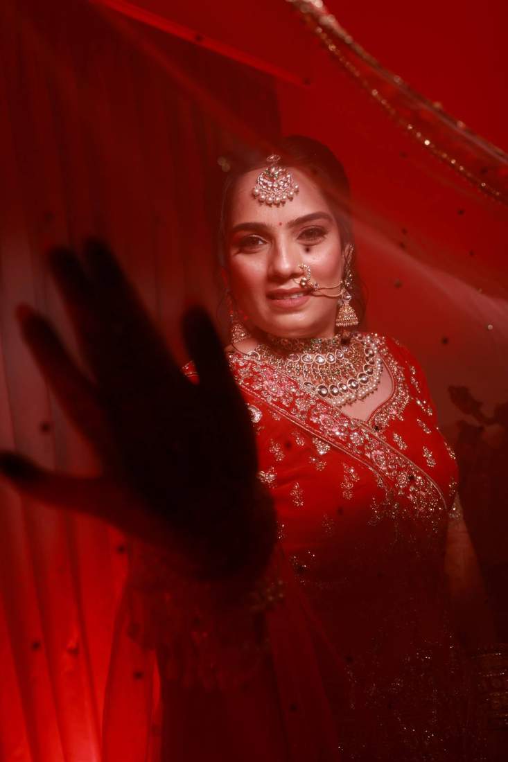 Artistic bridal portrait lit in red, with a silhouetted hand in the foreground
