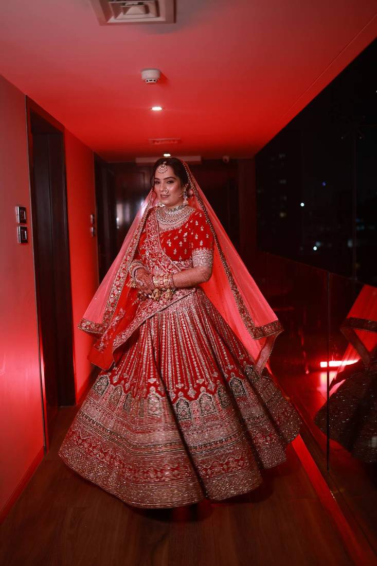 Bride twirling in a red bridal lehenga in a corridor