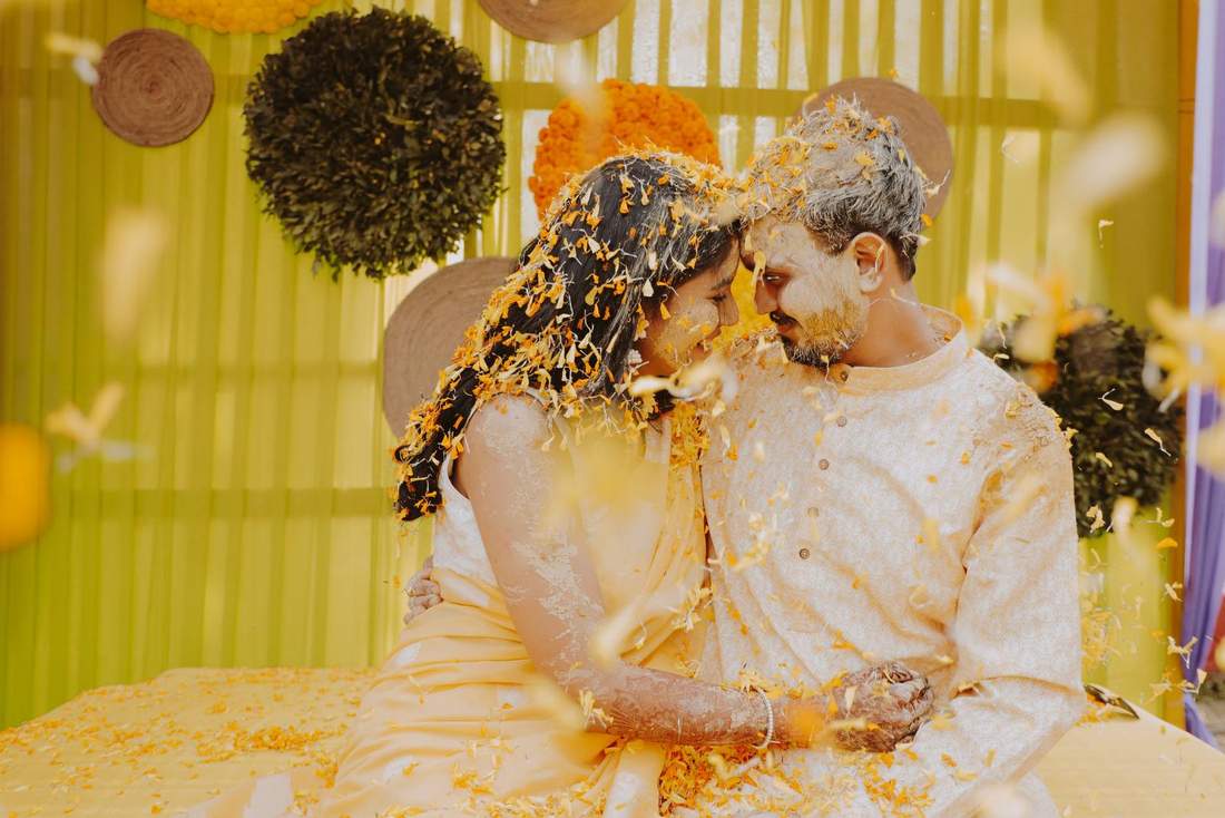 Couple, foreheads together, covered in yellow flower petals
