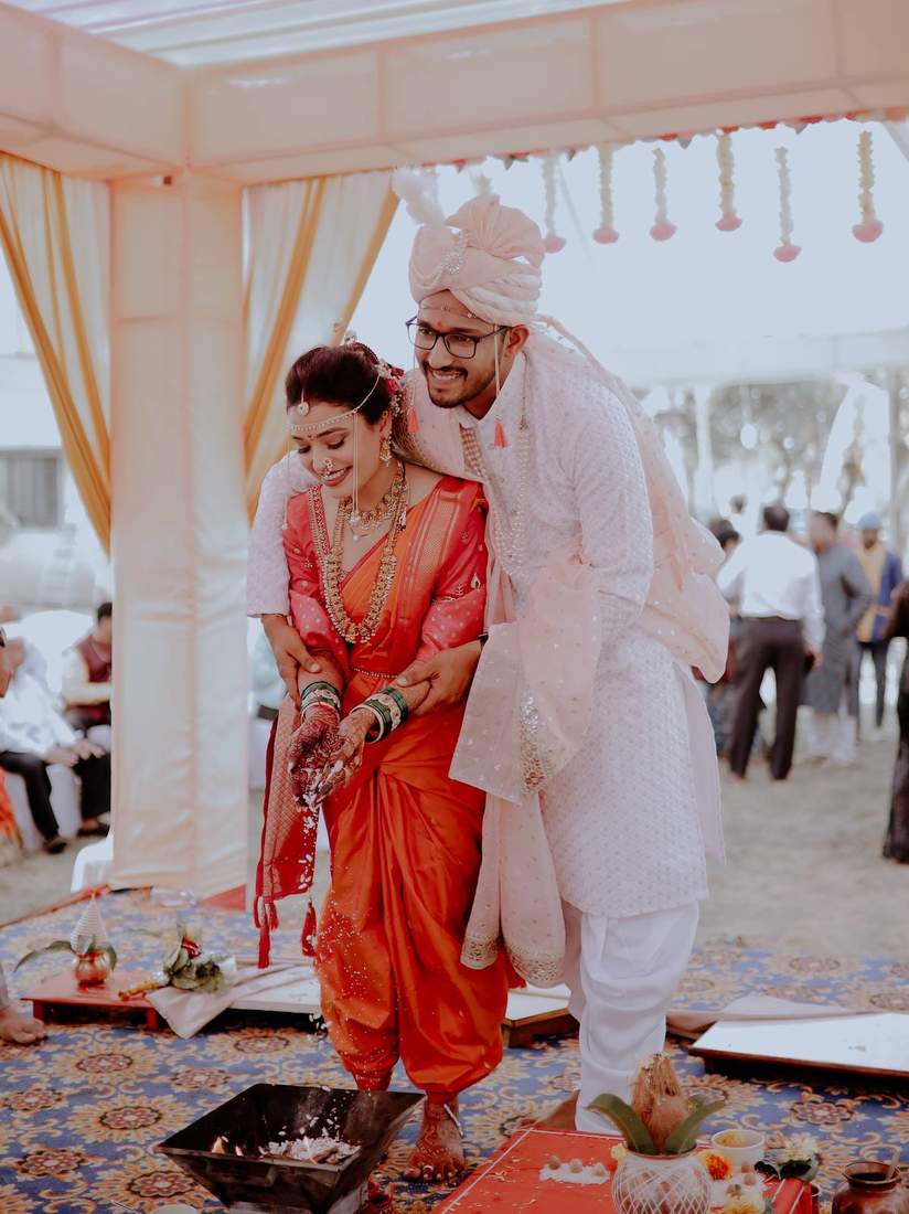 Maharashtrian wedding ritual with the couple pouring grain by the sacred fire