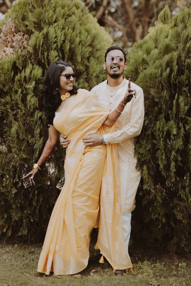 Bride and groom sharing a playful, laughing moment in yellow outfits