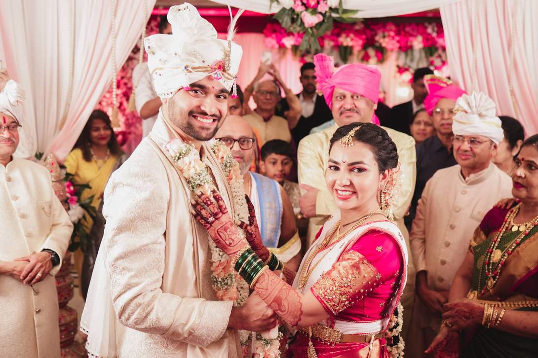Bride and groom holding hands at the mandap under a pink floral canopy