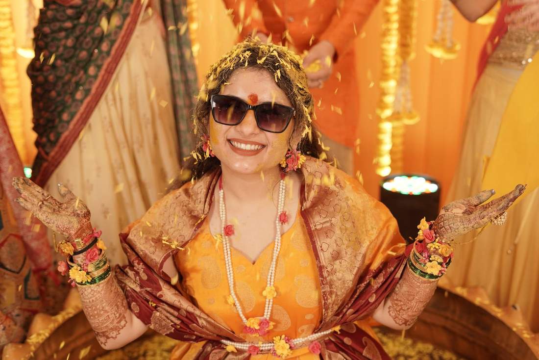 Close-up of bride in sunglasses laughing as yellow petals fall around her
