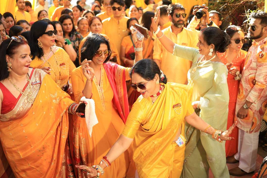 Guests in yellow and orange dancing together at the mehendi function