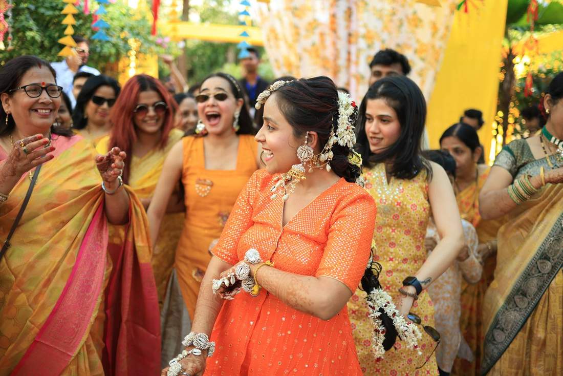 Bride in a bright orange outfit dancing joyfully with the crowd
