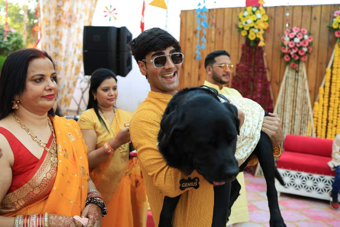 Groomsman carrying the family puppy dressed for the occasion