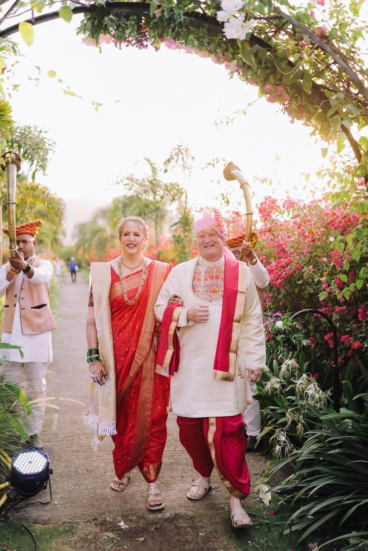 Wedding procession walking through a floral archway