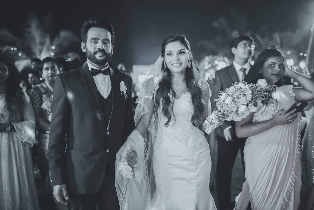 Black and white photo of bride and groom walking into their reception